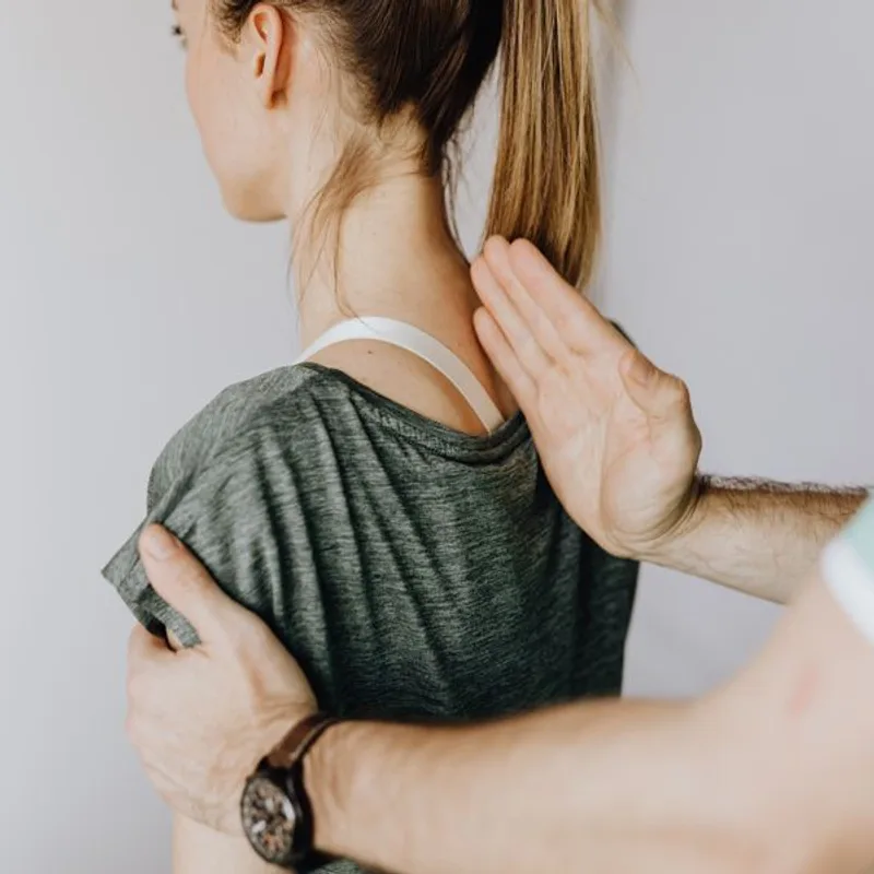 A chiropractor adjusts a patient's upper back